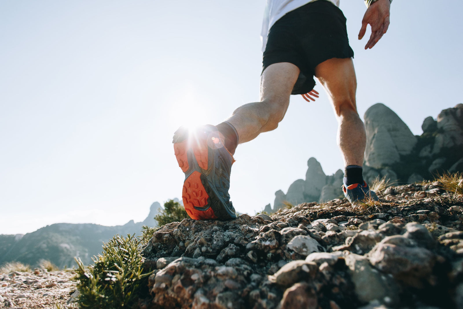 A man hiking up a rocky mountain in sturdy trail running shoes.