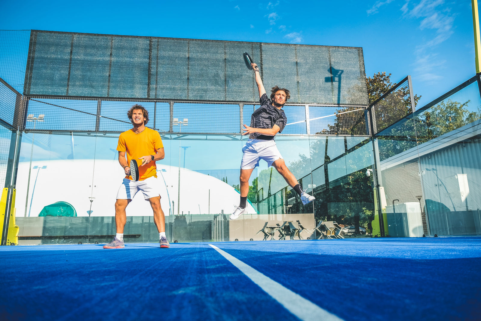 Two male padel players mid-game on padel court wearing the best padel shoes for men