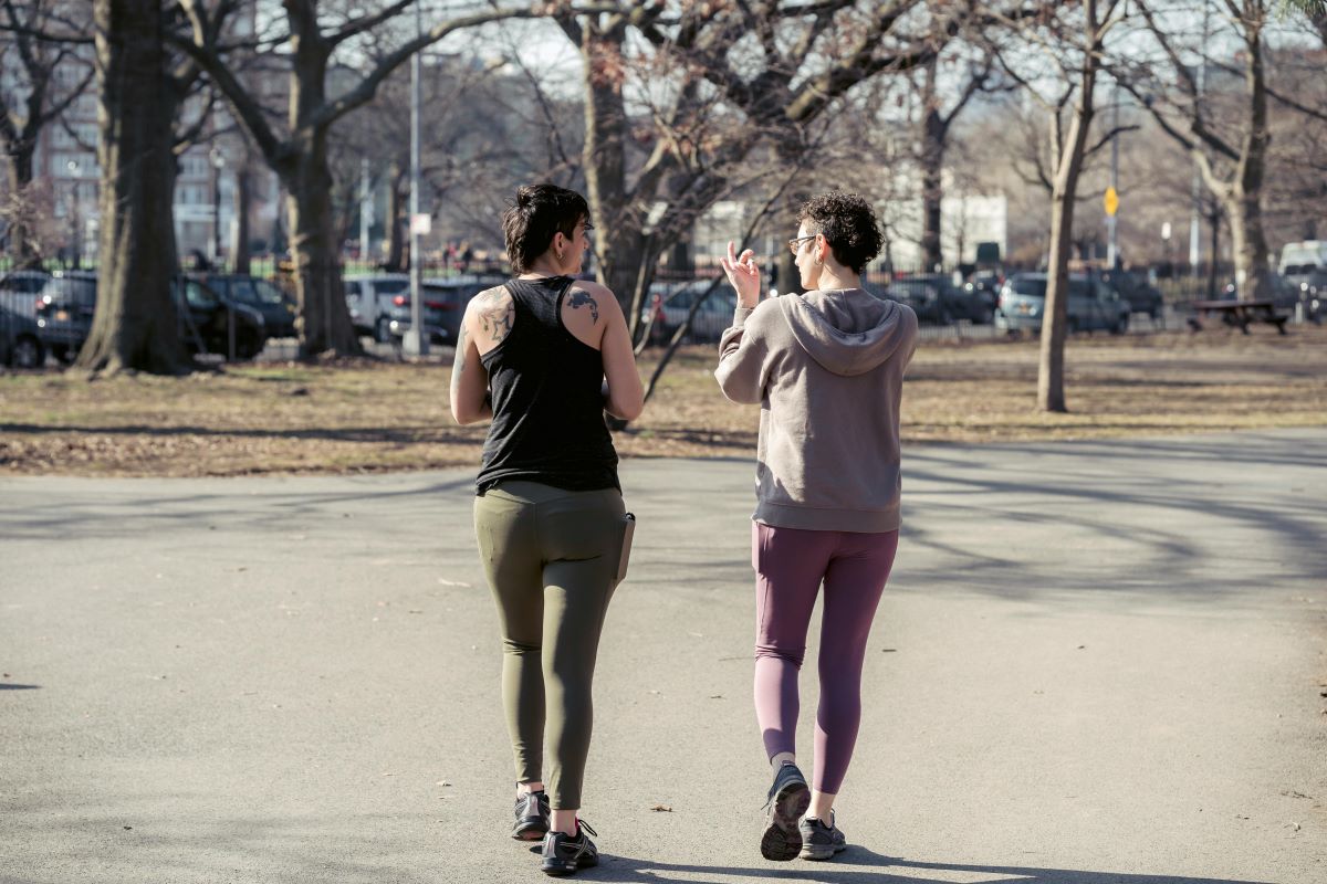 Two people enjoying a leisurely walk in the park dressed in athleisure wear.