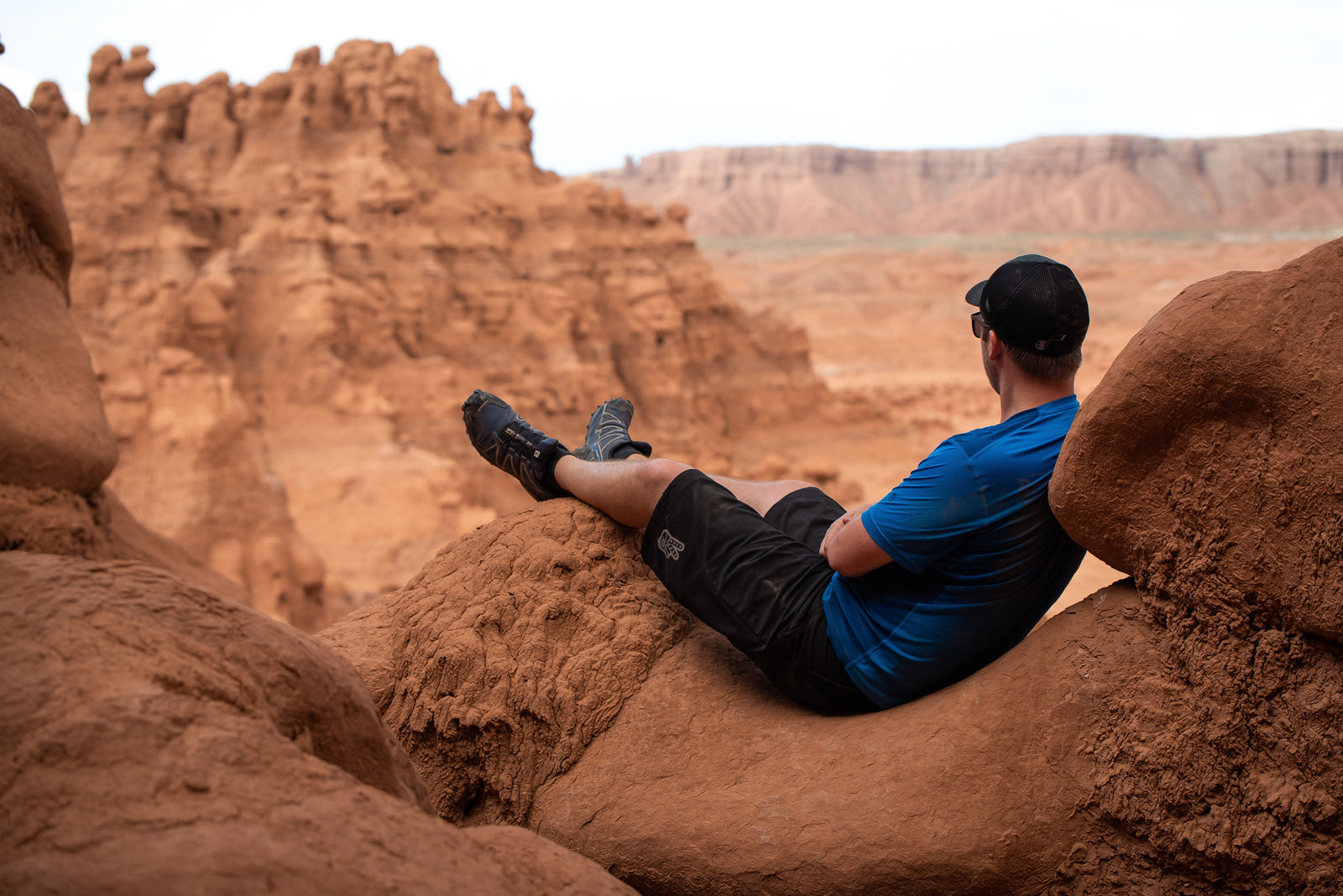 A man with Salomon shoes on sitting on a rock at a canyon