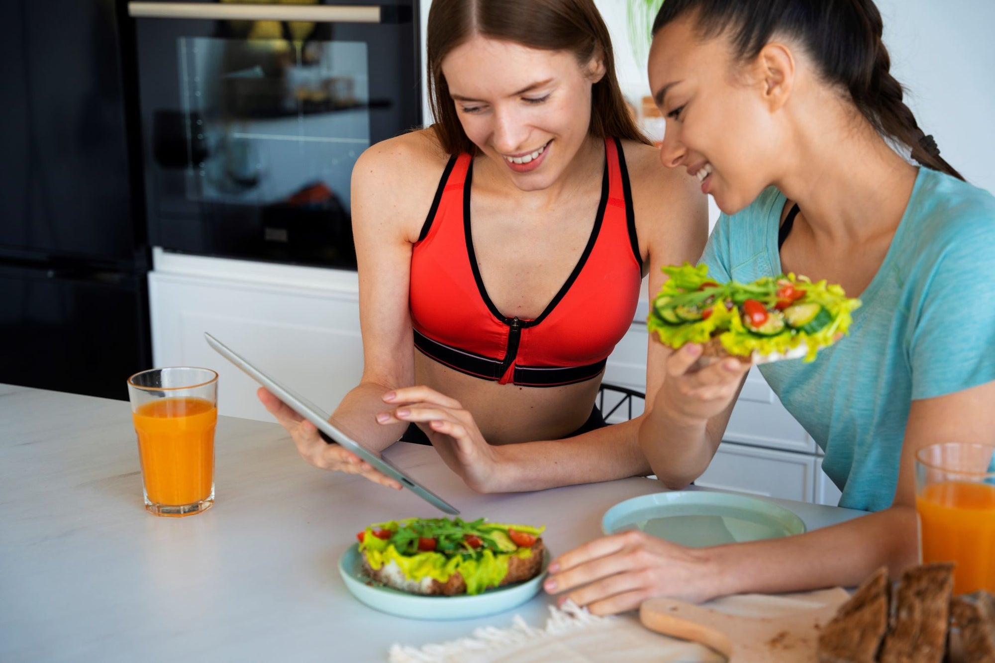 Two women discussing the best nutrition plan for training while enjoying healthy meals