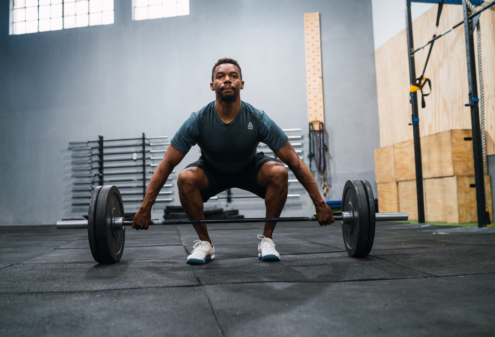 An African man squatting with a barbell wearing the best trainers for HIIT.