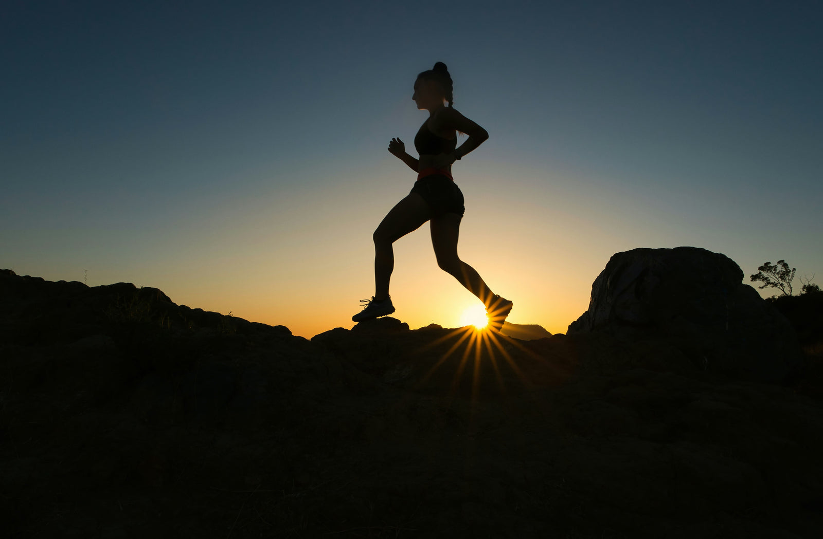 Silhouette of a woman running on a mountain at sunset wearing on cloud women's shoes