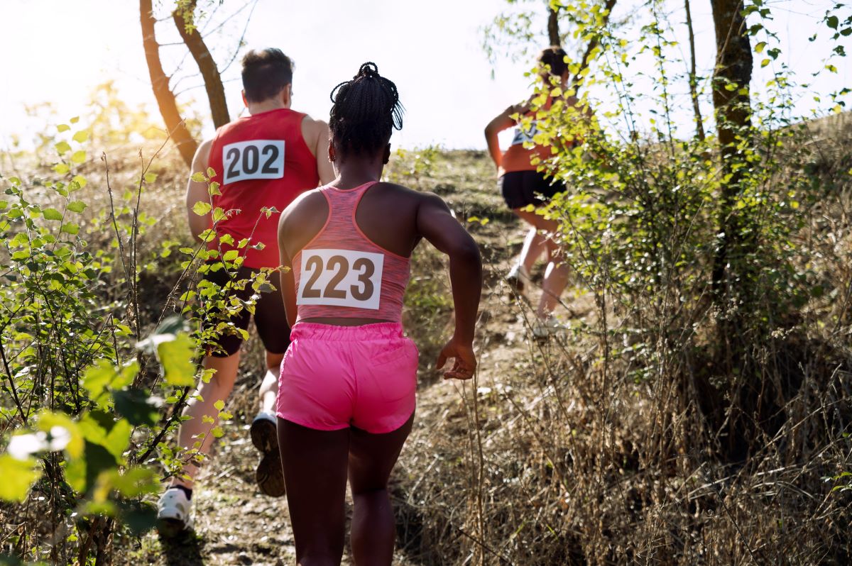 Numbered runners, with 223 in view, engaged in a trail running competition amid a leafy landscape.
