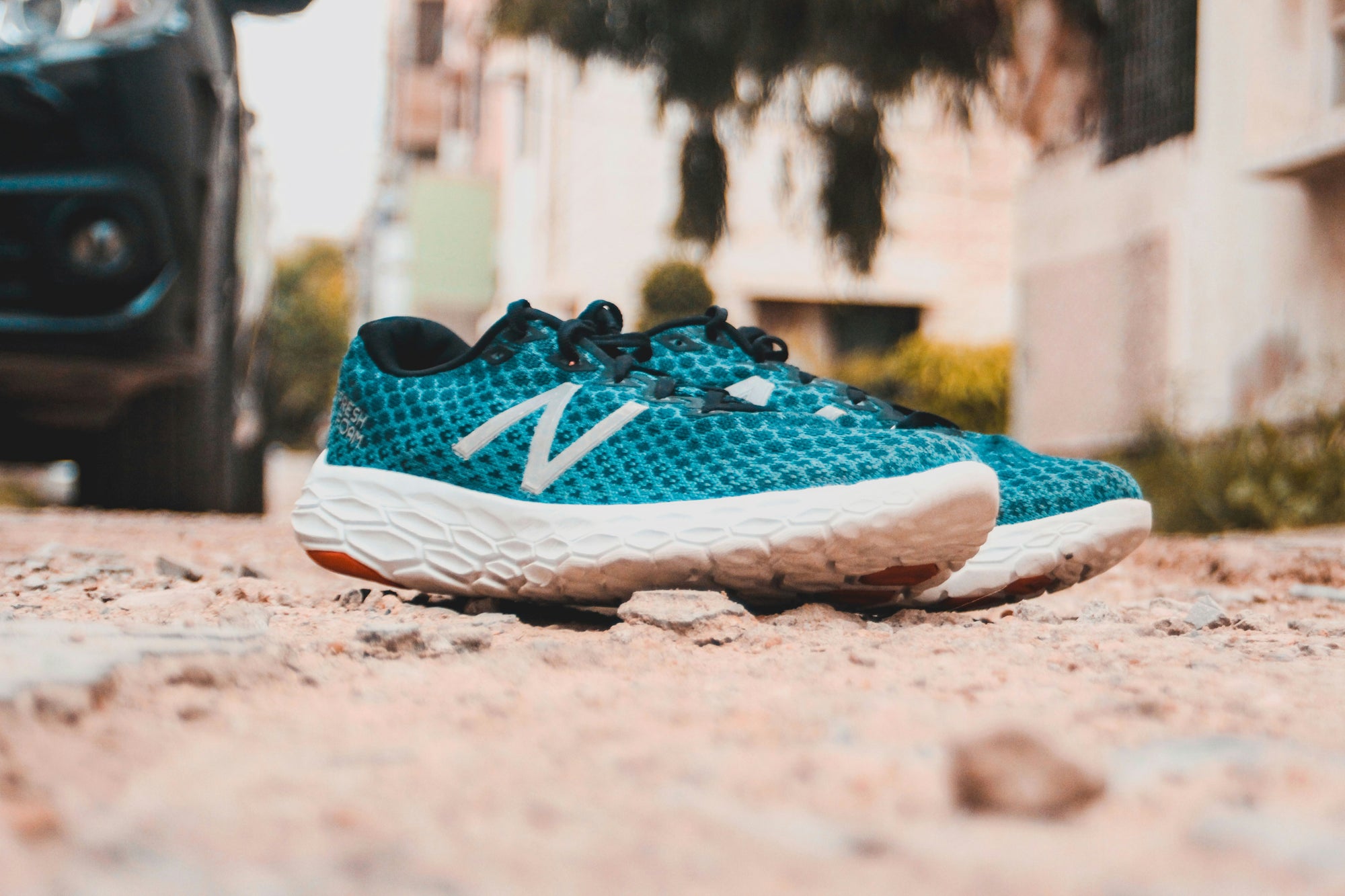 Blue and white New Balance Fresh Foam pair of sneakers on gravel pebbles
