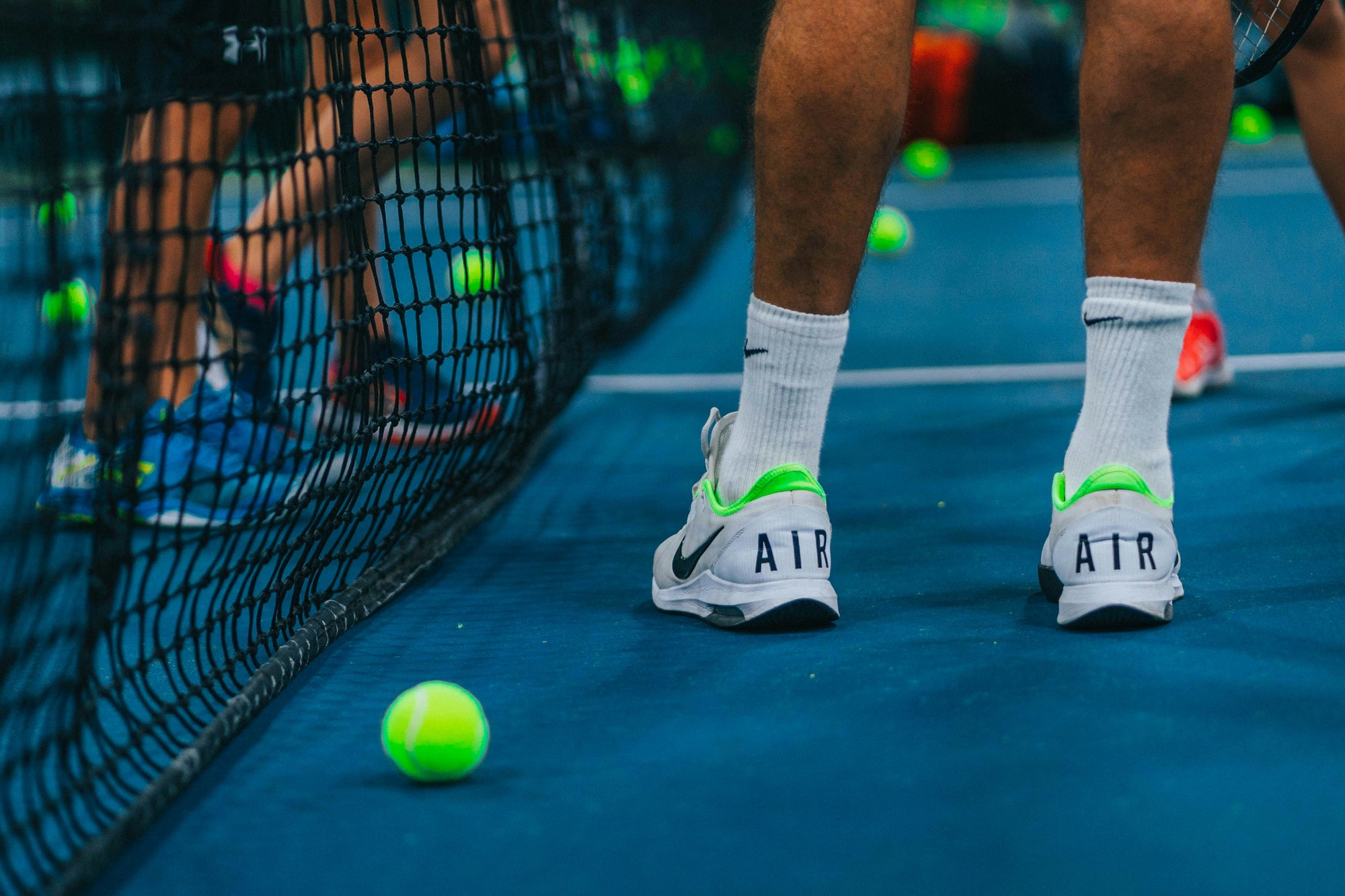 Men's tennis shoes by the court net