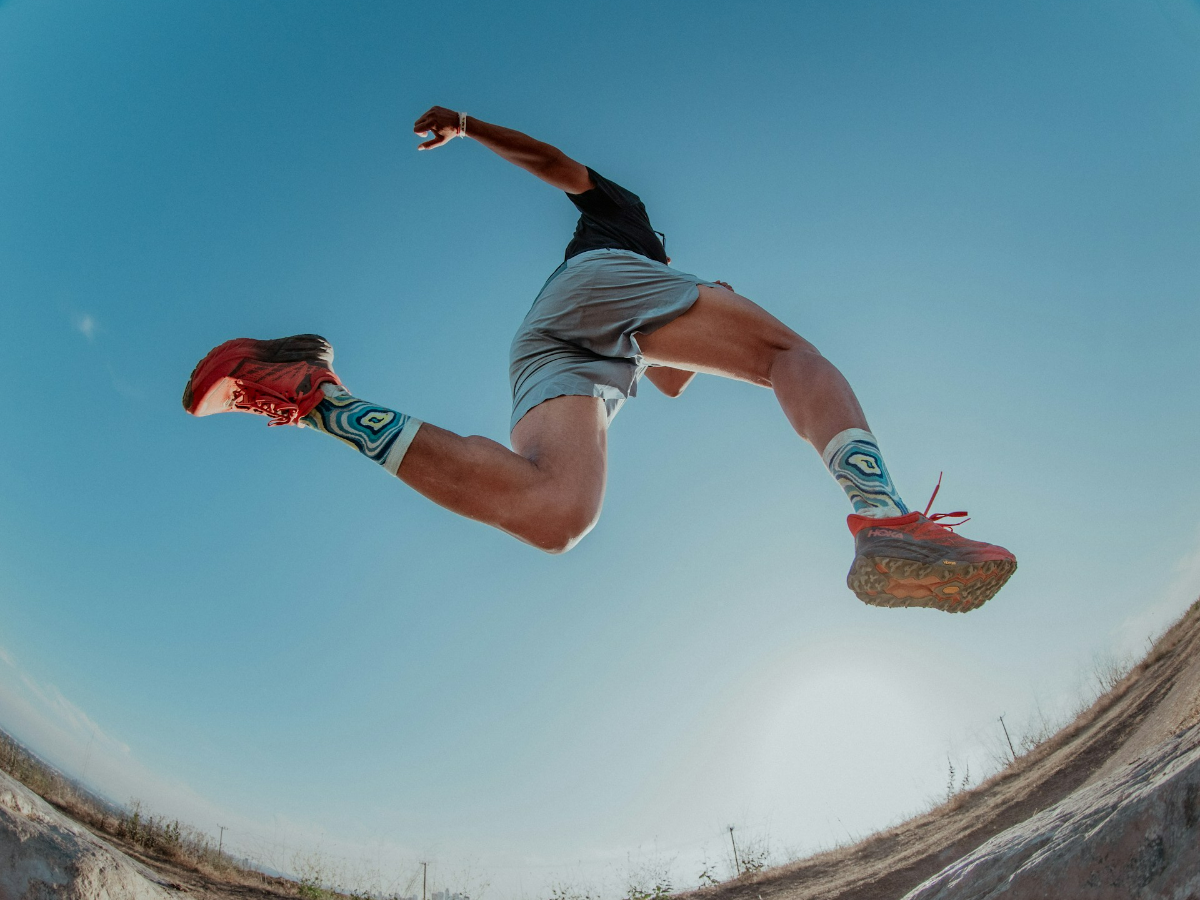 A bottom up shot of a man running with the best trail running shoes for gravel roads