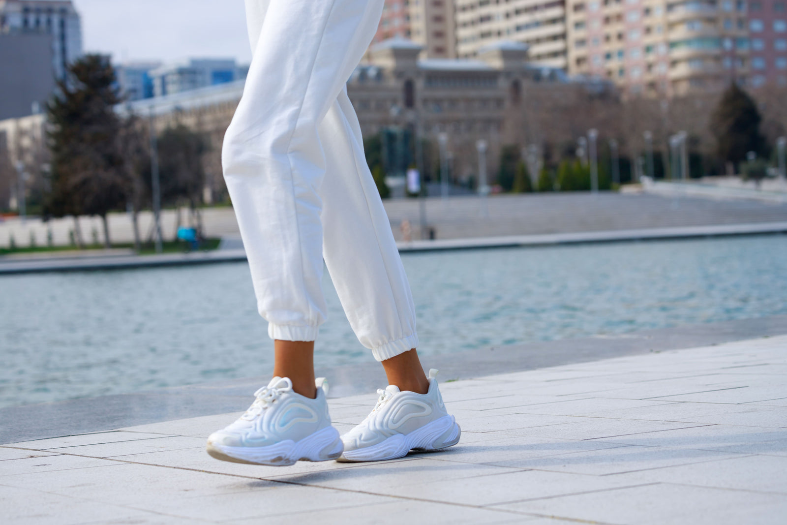 Female wearing white trousers, walking in white lifestyle shoes