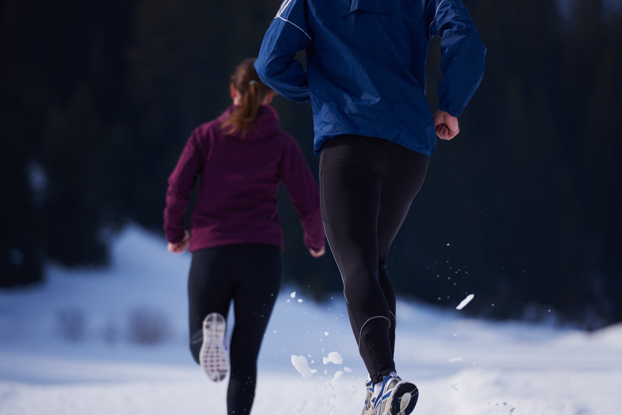 Two people jogging in winter wearing black running pants.