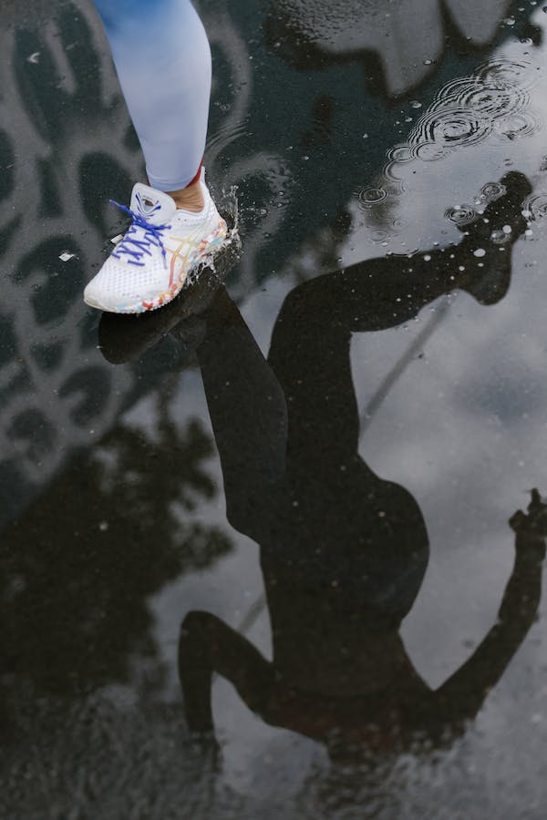 reflection of a person running with running shoes on a wet path