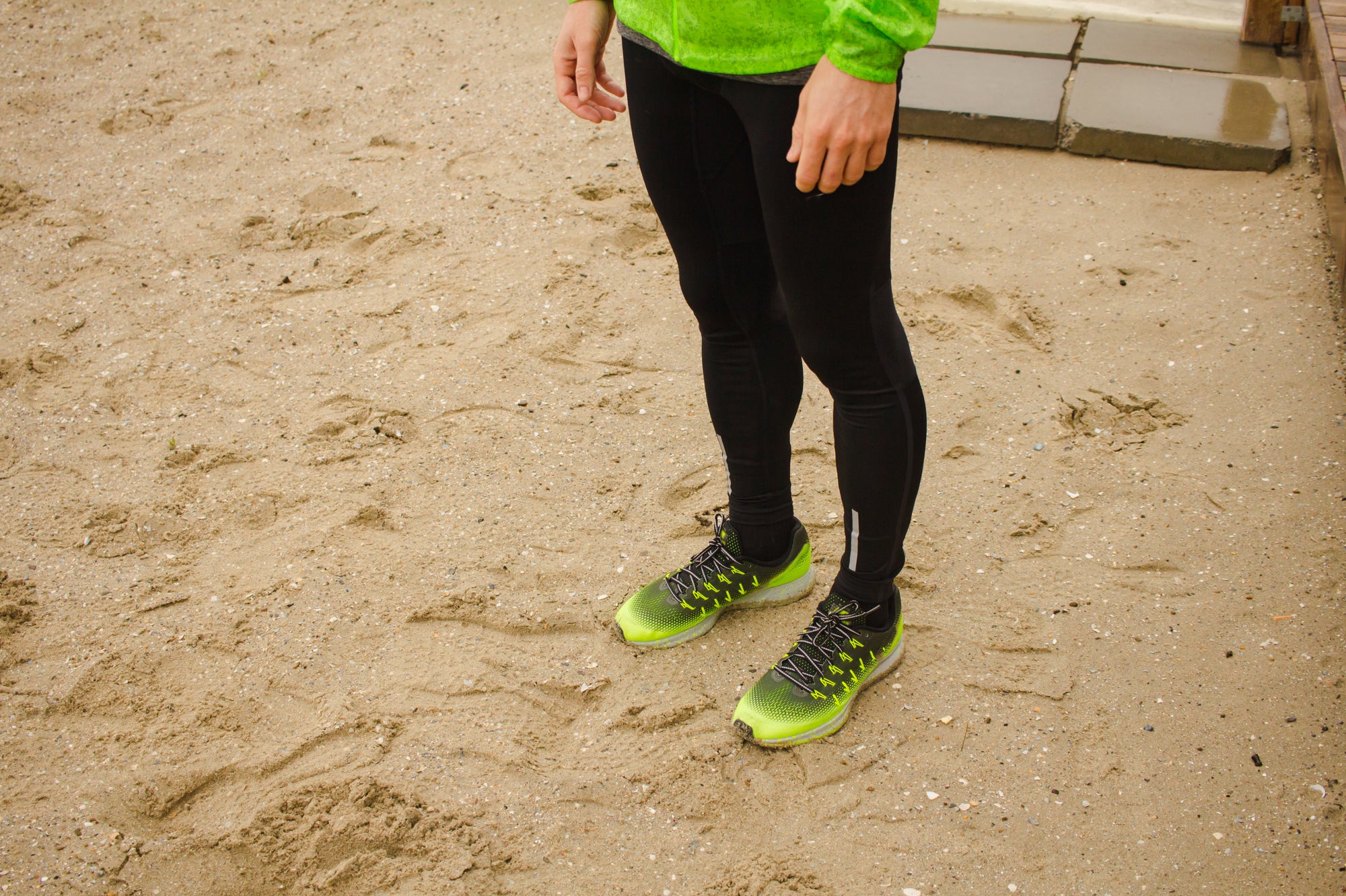 Man in tight black running pants and green shoes 