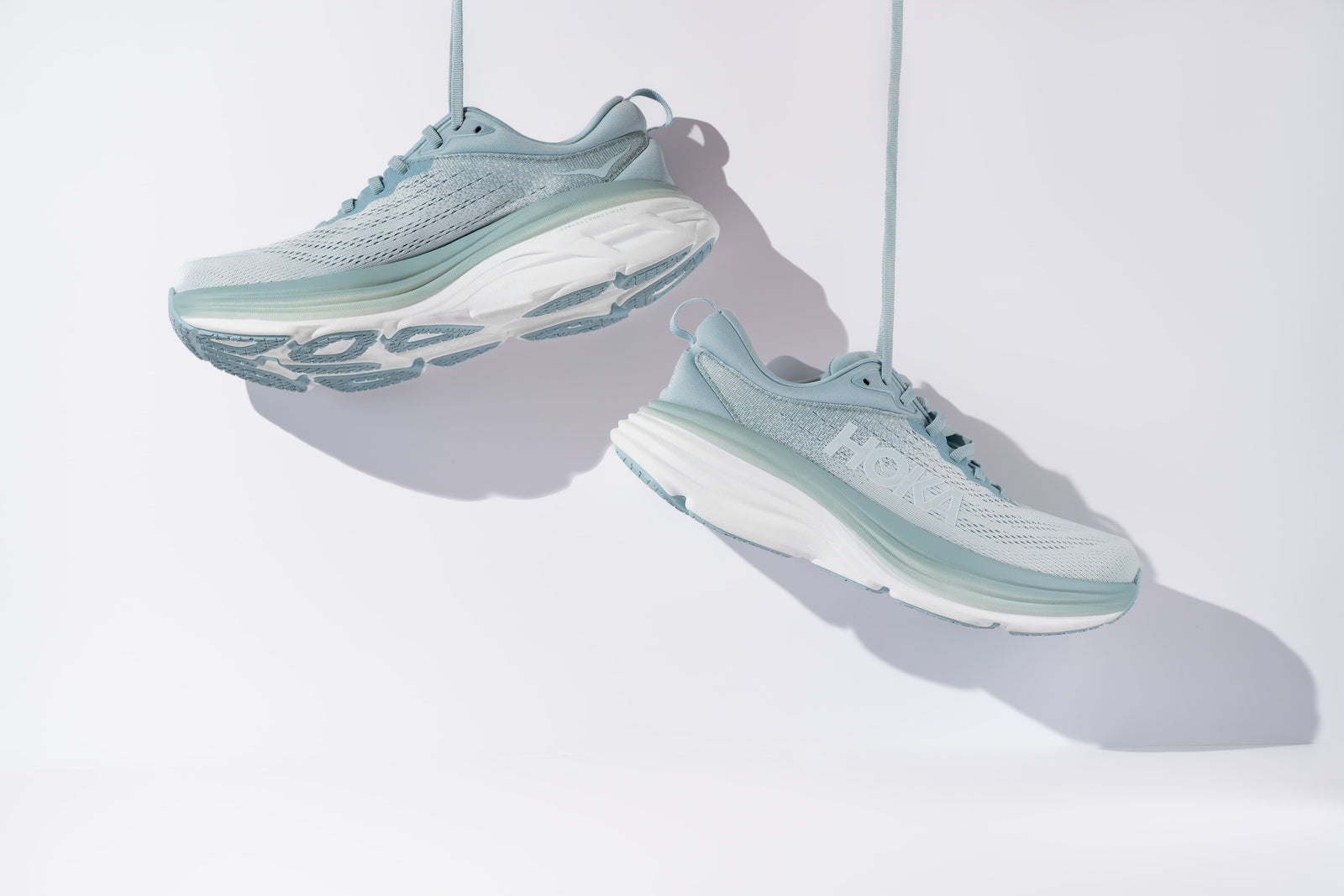  Hoka trail running shoes, hanging by their shoelaces, on display