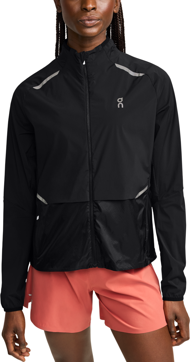 Woman wearing a black performance women&#39;s jacket, with a sleek design. With a breathable mesh panel.